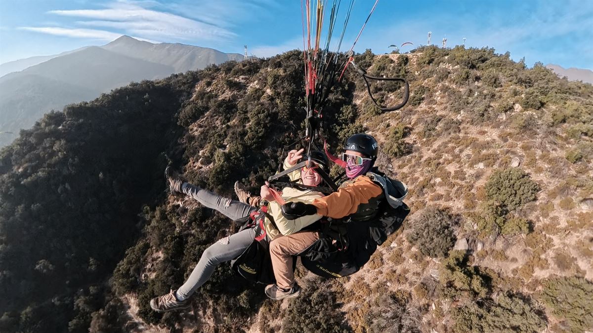 Piloto y pasajera en vuelo tándem sobre el valle de Las Vizcachas